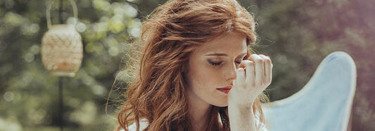 Frau riecht Parfum an ihrem Handgelenk